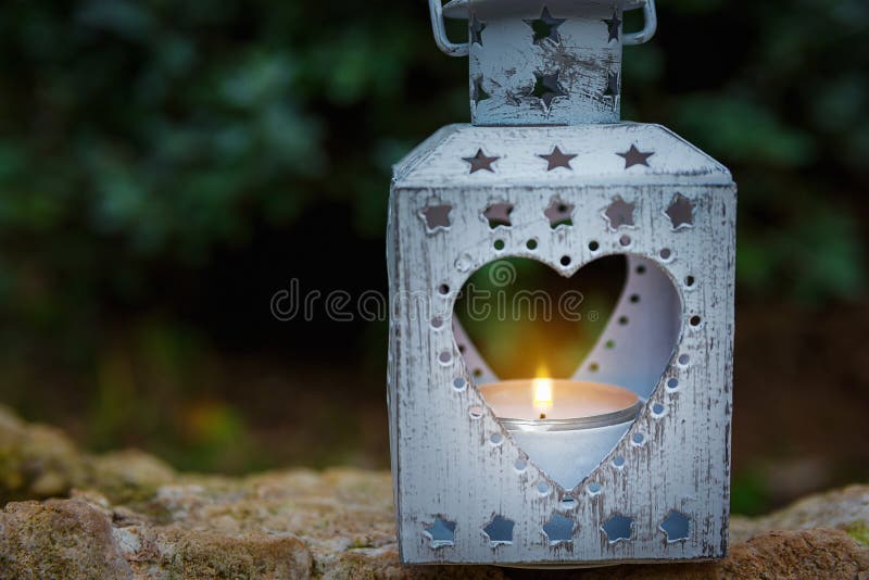 Vintage Metal Heart Shape Candle Holder Lit Burning Flame Standing on Stone in Garden.Valentine Mother`s Day