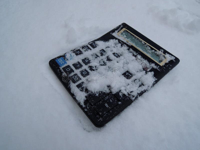 Vintage not working photocell calculator with snow-covered buttons stock image. Metaphorical image symbolizing financial crisis