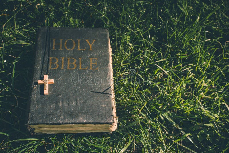 Vintage old holy bible book, grunge textured cover with wooden christian cross. Retro styled image on grass background. royalty free stock photo Vintage old holy bible book, grunge textured cover with wooden christian cross. Retro styled image on grass background. royalty free stock photo