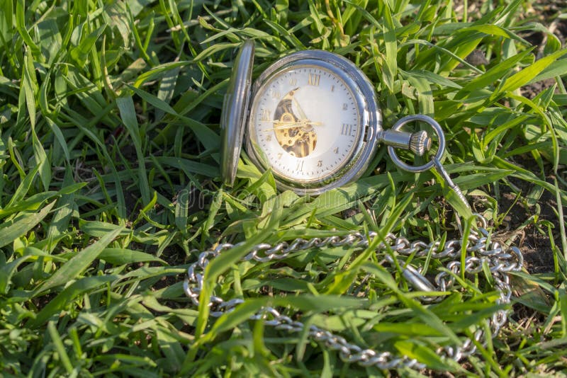 Vintage pocket watch in male hand on a background of green grass. Steampunk watch. Sunny summer day. The clock mechanism is stock photos Vintage pocket watch in male hand on a background of green grass. Steampunk watch. Sunny summer day. The clock mechanism is stock photos