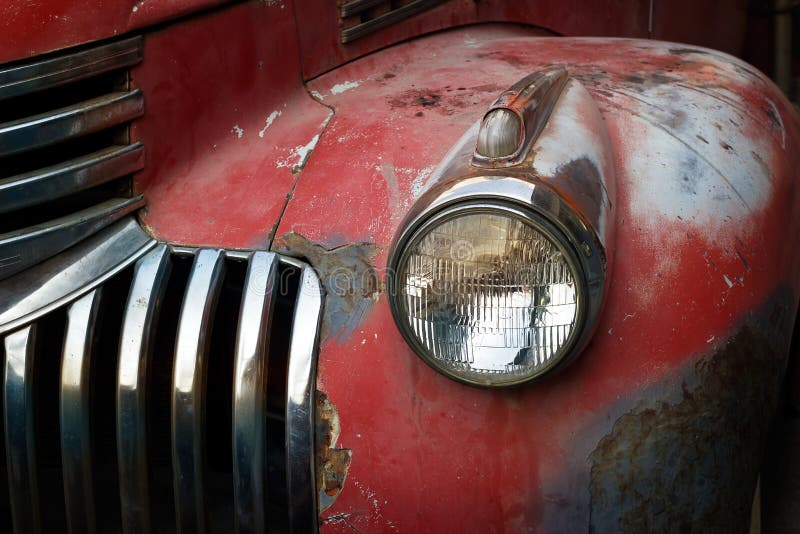 Vintage rusty red truck car with a new headlight, soft focus