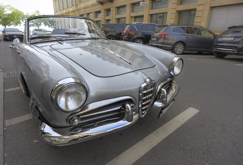 Vintage silver Alfa Romeo-konvertibel som är parkerad på en europeisk gatuort som fångar klassisk bilelegans och tidlös design arkivbild