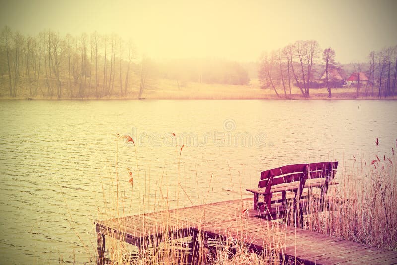 Vintage stylized photo of bench at the lake.