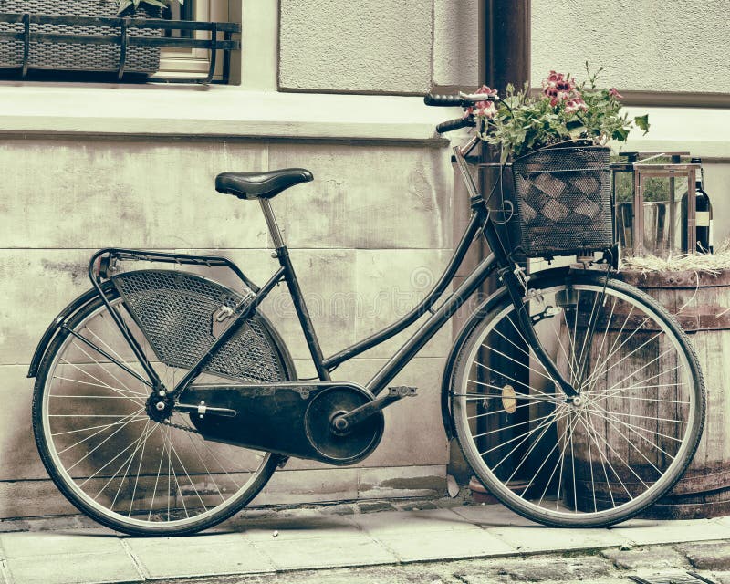 Vintage stylized photo of Old bicycle carrying flowers