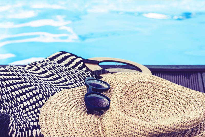 Vintage summer wicker straw beach bag, sun glasses, hat near swimming pool, tropical background
