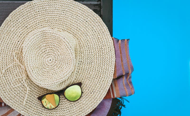 Vintage summer wicker straw beach hat, sun glasses, cover-up beachwear wrap near swimming pool, tropical background