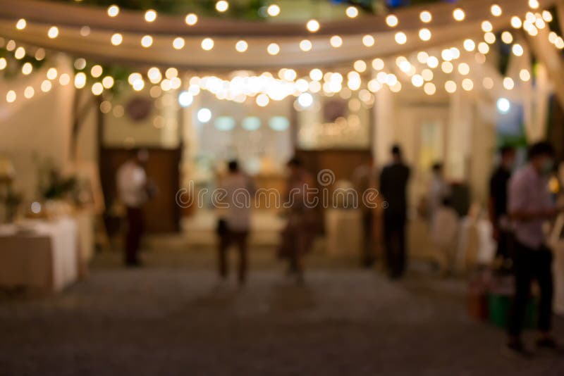 Vintage tone blur image of food stall at night festival with bokeh for background usage. Festival Event Party with People Blurred Background. Blur people having sunset beach party in summer vacation.