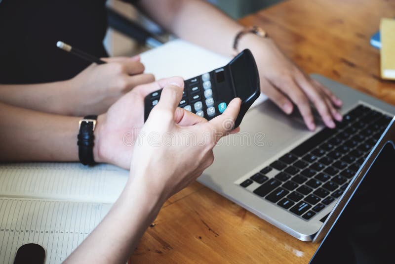 Vintage tone effect with business man using calculator to calculate budget and partnership using computer at work stock image