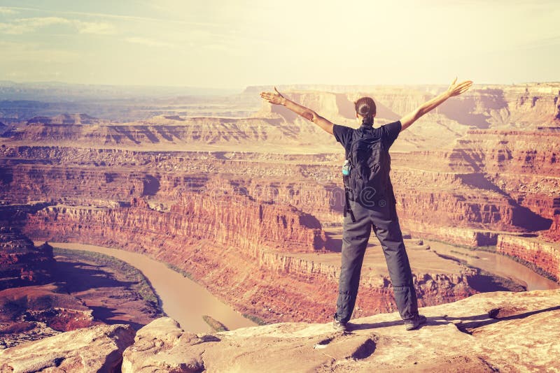 Vintage toned woman standing on a cliff with hands up. stock image Vintage toned woman standing on a cliff with hands up. stock image