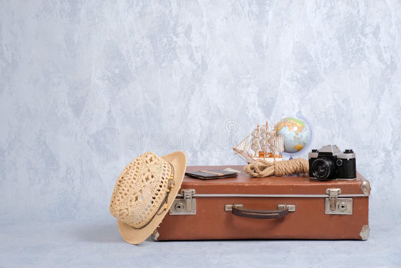 Vintage travel bag with summer marine accessories: retro camera, toy sailboat, straw hat, passport with money. Travel or tourism