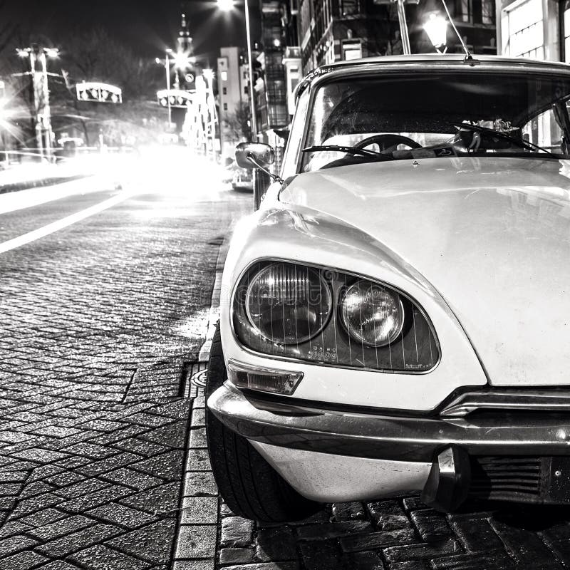 Vintage white car parked in center of Amsterdam at night time. Black-white photo