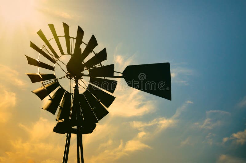 Windmill silhouette against morning sun in rural Texas. Vintage windmill silhouette against golden glowing morning sun in rural Texas