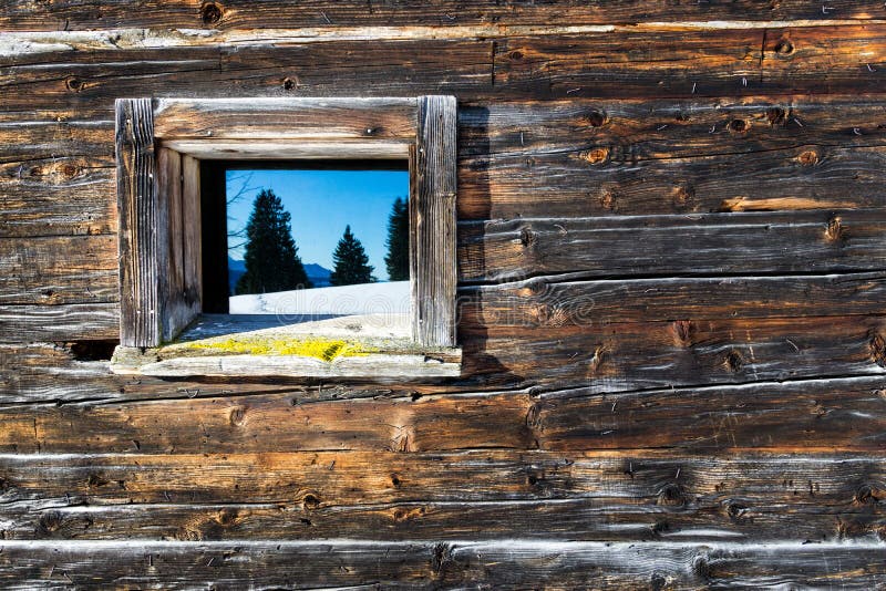 Vintage window of old wooden cabin mirrors winter mountain landscape. Wooden rustic background. stock image