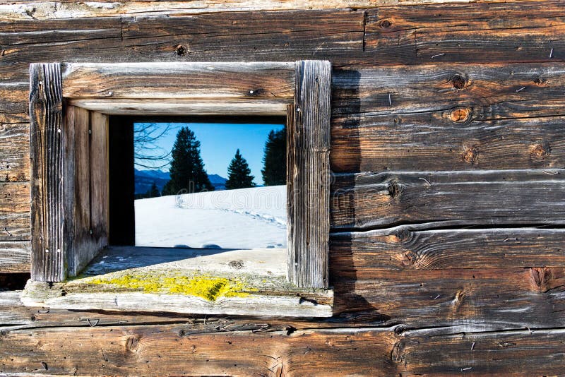 Vintage window of old wooden cabin mirrors winter mountain landscape. Wooden rustic background.