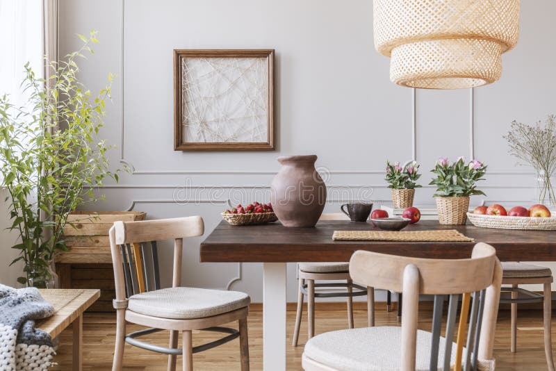 Vintage wooden chairs in living room with long table with strawberries, apples, vase and flowers on it, real photo