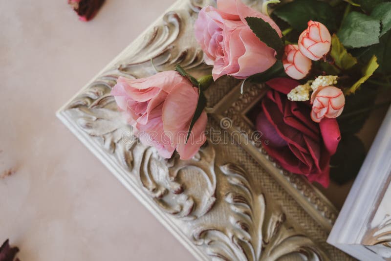 Corner of vintage picture frame and flowers on pastel pink backdrop. Romantic concept. Valentine day, anniversary card background.