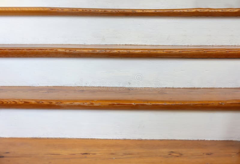 Vintage wooden stair with brown plank tread and white riser. Wood shelf on white painted wall