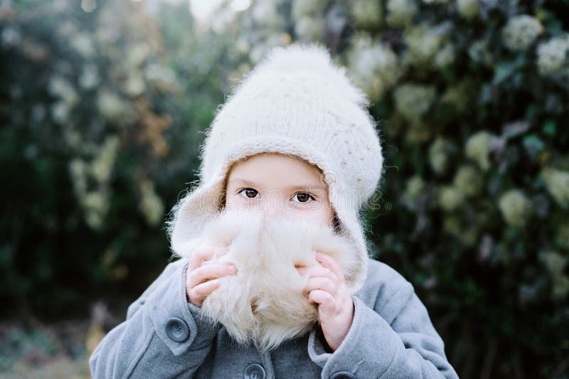 Vinter för flickahattstående barnet dolde hans framsida bak pompoms trees för park för den dagfrostjanuari naturen övervintrar snöig