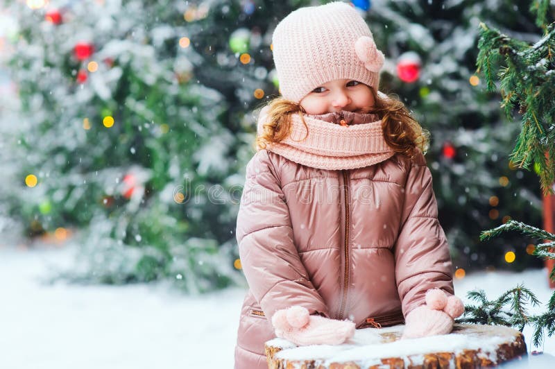 Vinter- och julståenden av lyckligt behandla som ett barn att gå för flicka som är utomhus- i den snöig dagen, staden som dekorer royaltyfri foto