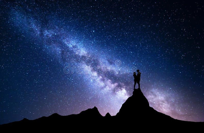 Milky Way with silhouette of people. Night landscape with starry sky. Standing man and woman on the top of mountain. Hugging couple against milky way. Beautiful galaxy. Universe. Travel. Bright stars. Milky Way with silhouette of people. Night landscape with starry sky. Standing man and woman on the top of mountain. Hugging couple against milky way. Beautiful galaxy. Universe. Travel. Bright stars