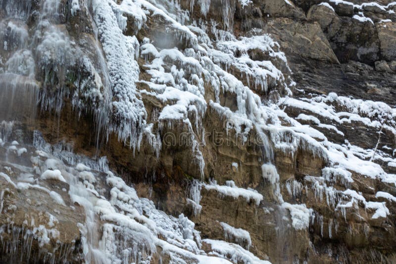 Vinterlandskapet i bergen är vackert, med träd som berövar vattenfall, snö som faller royaltyfri bild