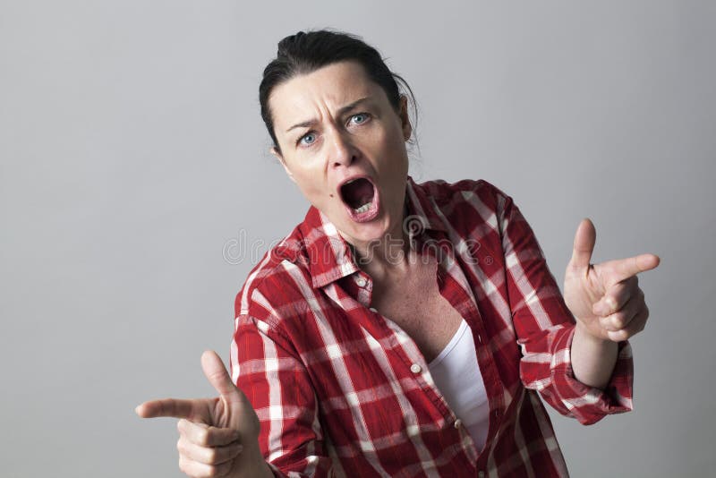 Violent middle aged woman shouting with fighting hand gestures with fingers shooting like guns in the foreground
