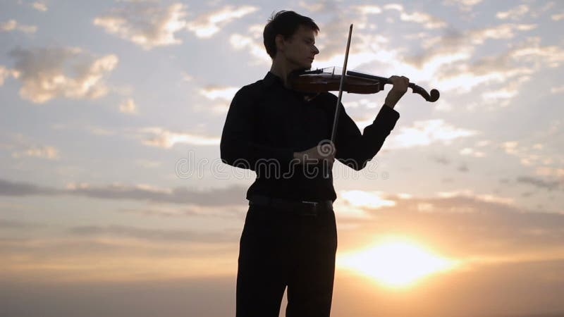 Violinist playing at sunset on the roof. Music, art.