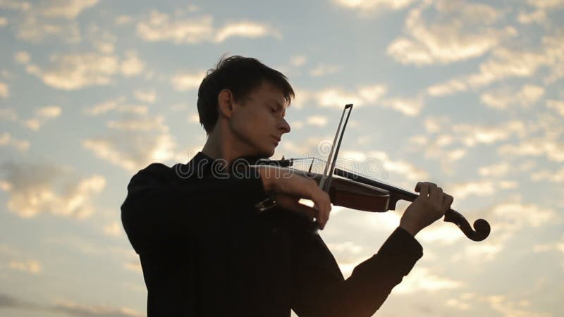 Violinist plays against the sunset. Violin on sunset.