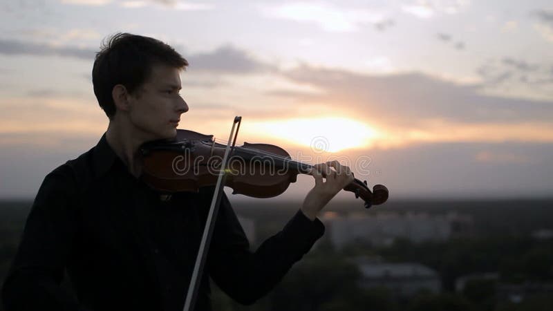 Violinist puts musical instrument on his shoulder and begins to play