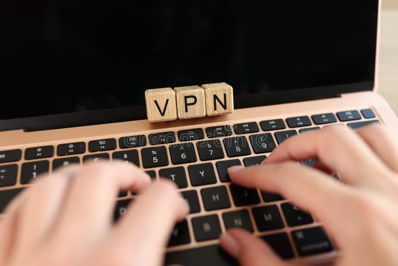 Virtual private network for a secure, encrypted connection and online anonymity. Wooden cubes with VPN letters and user& x27;s hands on laptop keyboard.