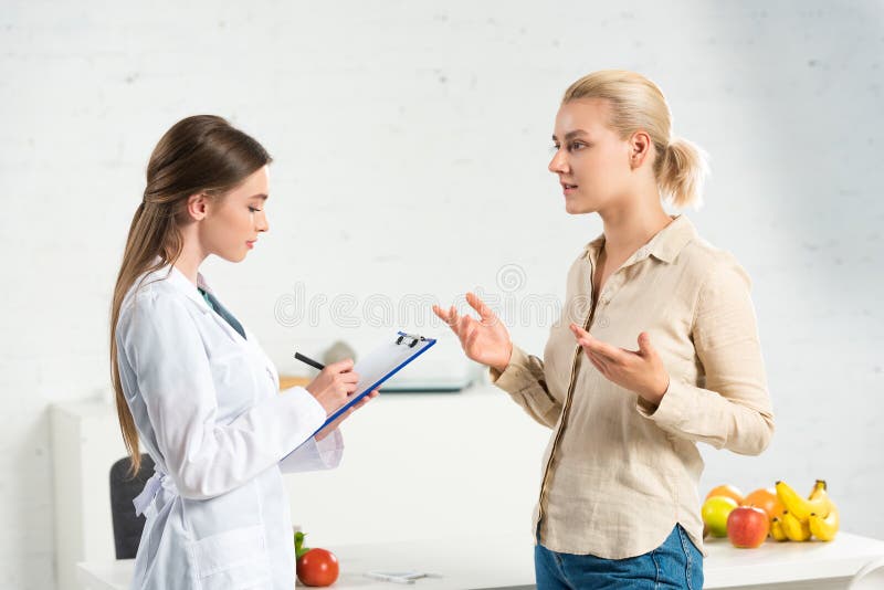 Visa dietitianskriften i vita rockar i Urklipp och patient royaltyfri fotografi