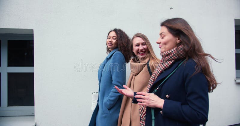 Visa glada, unga, attraktiva, kvinnliga vänner som möts under helger och går tillsammans längs stadens vägg. arkivfilmer