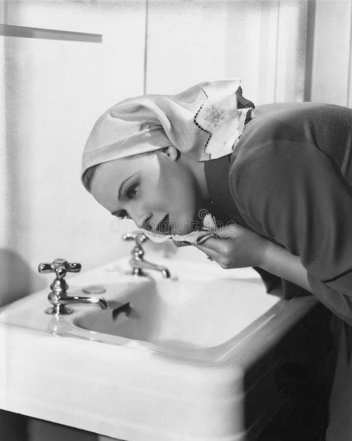Visage de lavage de femme au-dessus d'évier photo stock Visage de lavage de femme au-dessus d'évier photo stock