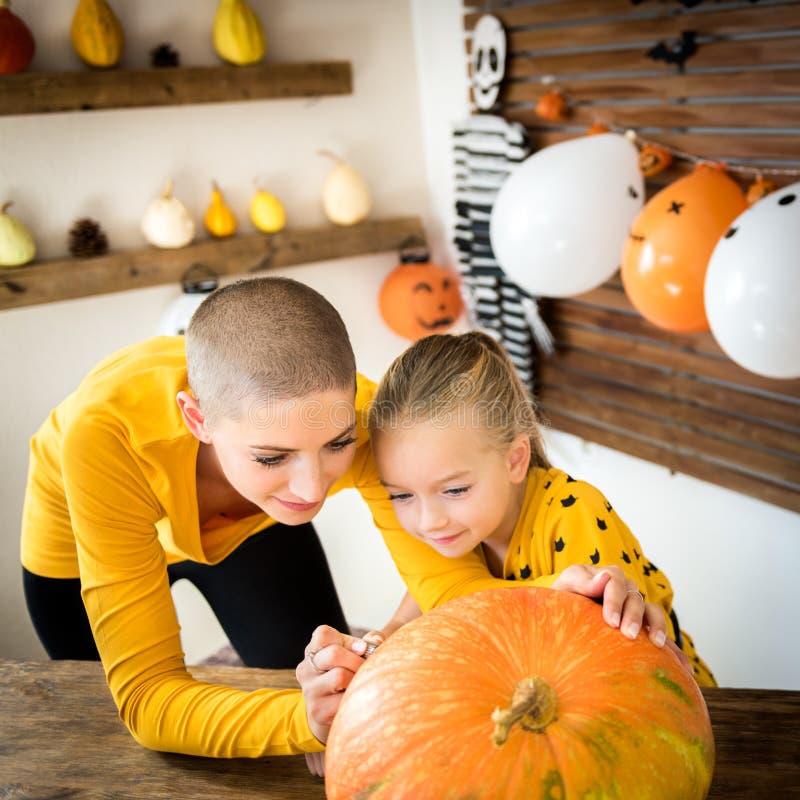 Visage souriant de dessin de mère et de fille sur un grand potiron de Halloween Famille décorant le potiron image stock Visage souriant de dessin de mère et de fille sur un grand potiron de Halloween Famille décorant le potiron image stock