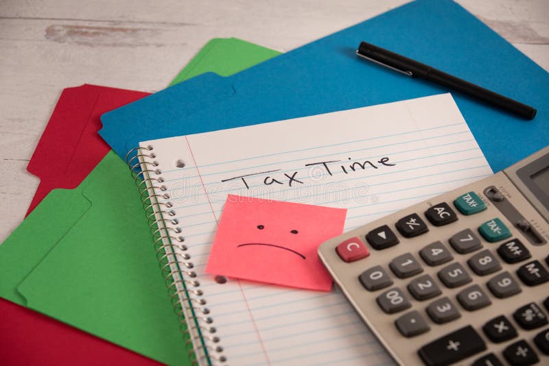 Tax time filing season sad face drawn on note pad office work supplies laying around calculator
file folders on wood desk. Tax time filing season sad face drawn on note pad office work supplies laying around calculator
file folders on wood desk