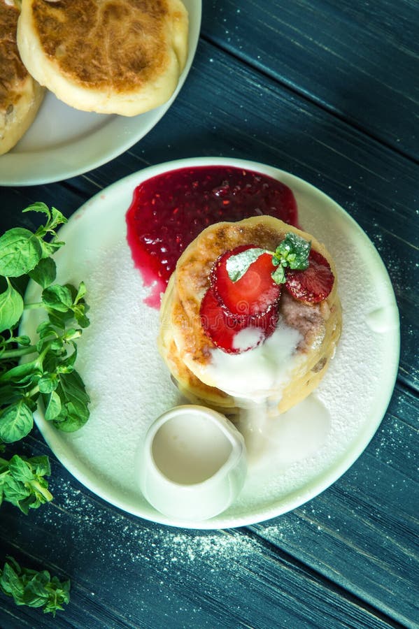 Visi?n superior Cierre para arriba Crepes rústicas del queso del desayuno, vertidas con crema y adornadas con las fresas imágenes de archivo libres de regalías Visi?n superior Cierre para arriba Crepes rústicas del queso del desayuno, vertidas con crema y adornadas con las fresas imágenes de archivo libres de regalías