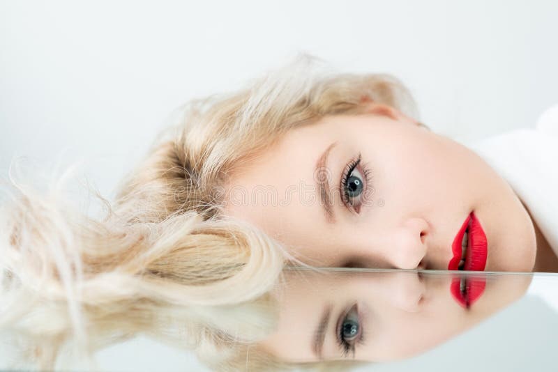 Vision correction. Eye laser surgery. Eyesight treatment. Ophthalmic procedure. Art portrait of blonde woman face with red lips makeup with blur mirror reflection isolated on light background. Vision correction. Eye laser surgery. Eyesight treatment. Ophthalmic procedure. Art portrait of blonde woman face with red lips makeup with blur mirror reflection isolated on light background.