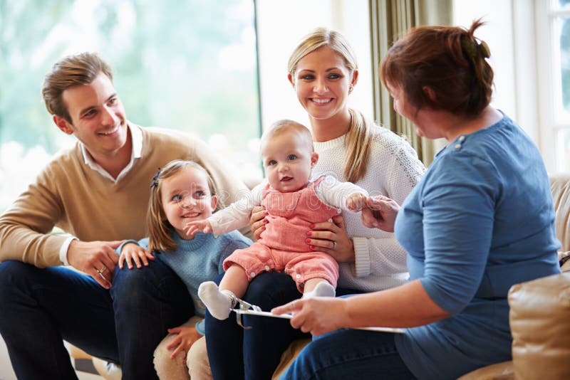 Visitante de la salud que habla con la familia con el bebé joven imágenes de archivo libres de regalías Visitante de la salud que habla con la familia con el bebé joven imágenes de archivo libres de regalías