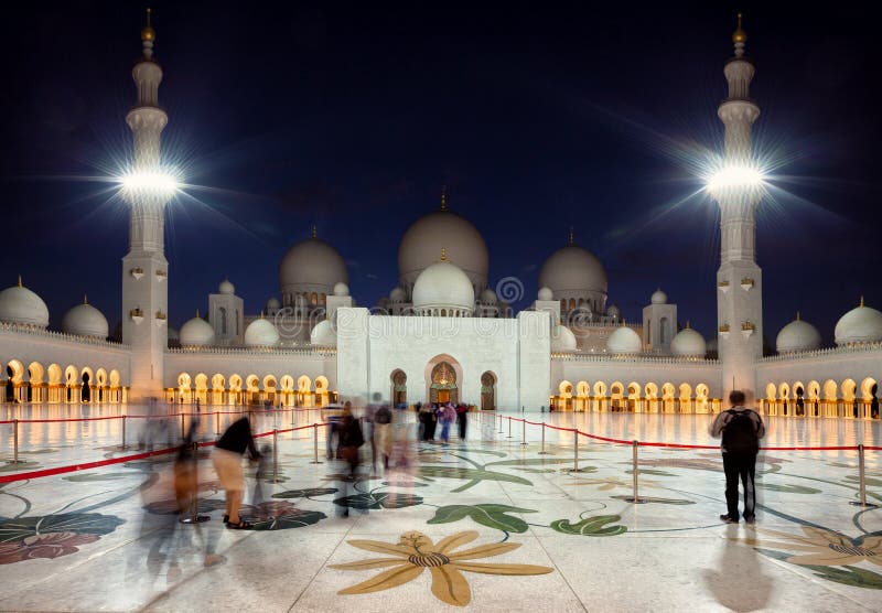 Visitantes que entran en la mezquita magnífica de Zayed en Abu Dhabi de emiratos en la oscuridad foto de archivo libre de regalías Visitantes que entran en la mezquita magnífica de Zayed en Abu Dhabi de emiratos en la oscuridad foto de archivo libre de regalías