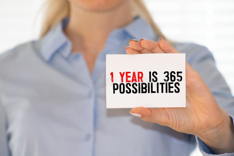 Business card with text 1 Year is 365 Possibilities lying on blue notebook. Business card with text 1 Year is 365 Possibilities lying on blue notebook