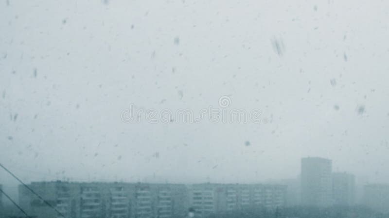 Visión desde la ventisca de la nieve de la ventana en ciudad Nevadas pesadas y mún tiempo del invierno