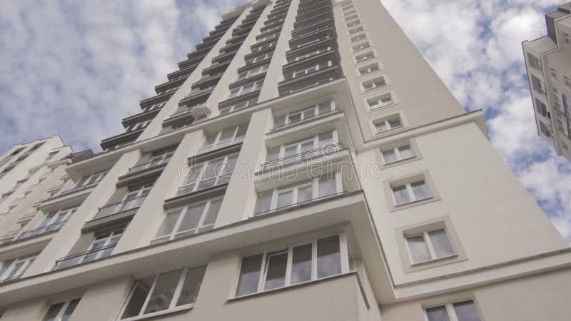 Visión en la nueva alta casa multi del piso con la reflexión del cielo en las ventanas