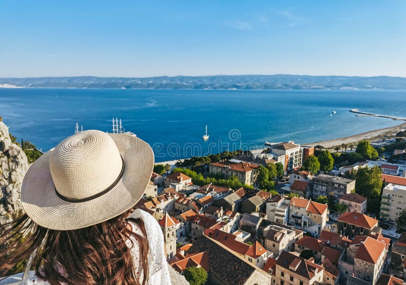 Visión trasera de la mujer parada en un mirador sobre la ciudad costera de omiscarón en croacia durante las vacaciones de verano fotos de archivo libres de regalías