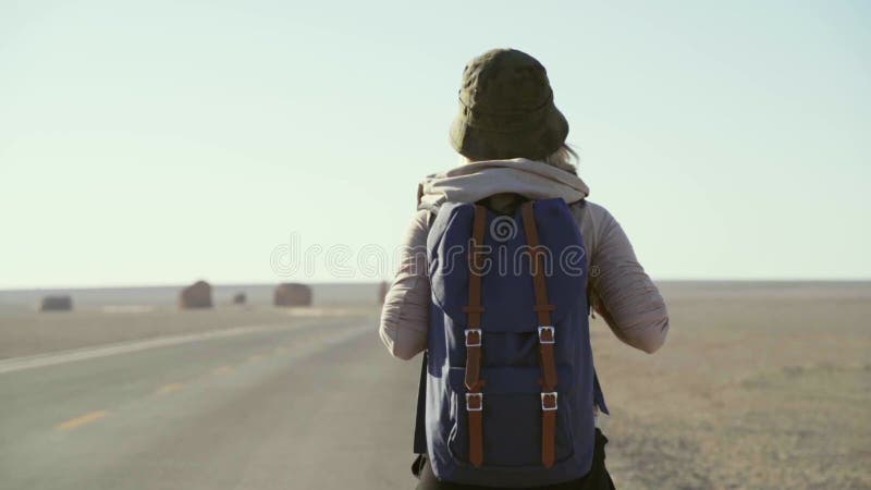 Visión trasera de una mujer viajera asiática caminando por una carretera desierta metrajes