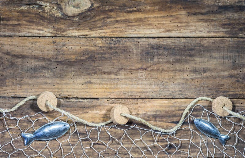 Nautical maritime background with fishing net and fish decoration on rustic brown wooden background and place for text. Nautical maritime background with fishing net and fish decoration on rustic brown wooden background and place for text.