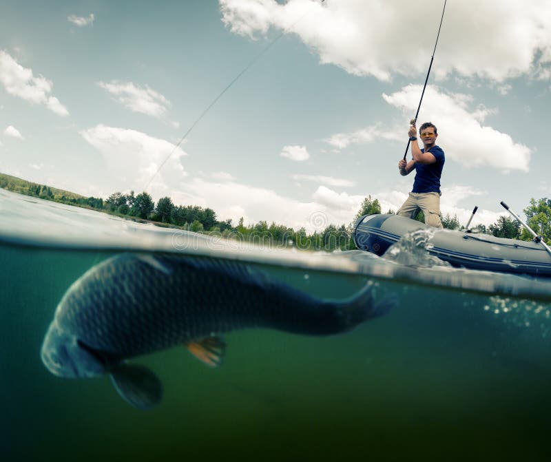 Young man fishing from the boat in the pond. Underwater split shot with fish on the foreground (fish is out of focus). Young man fishing from the boat in the pond. Underwater split shot with fish on the foreground (fish is out of focus)