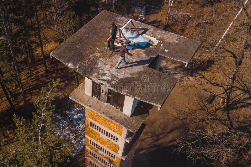 Aerial drone view of daredevils on the top of an abandoned ski jumping hill in siska, slovenia. dangerous maneouvres and stunts on buildings. Aerial drone view of daredevils on the top of an abandoned ski jumping hill in siska, slovenia. dangerous maneouvres and stunts on buildings