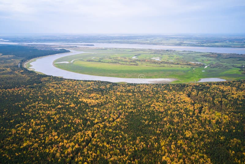 Aerial view of the winding valley of a flat river with a meandering riverbed. The floodplain of the river is swampy. Shooting from a drone. Aerial view of the winding valley of a flat river with a meandering riverbed. The floodplain of the river is swampy. Shooting from a drone.