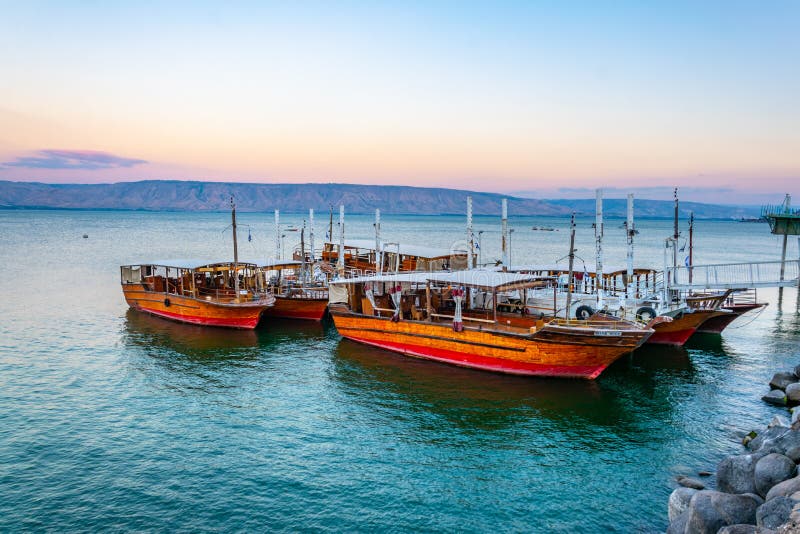 Vista al atardecer de un barco de madera flotando en el mar de galilee israel fotos de archivo