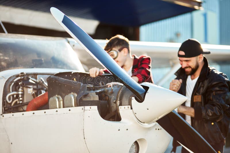 Vista alta vicina sull'ente anteriore dell'aeroplano dell'elica, del papà vago e del figlio stanti dietro fotografia stock libera da diritti Vista alta vicina sull'ente anteriore dell'aeroplano dell'elica, del papà vago e del figlio stanti dietro fotografia stock libera da diritti